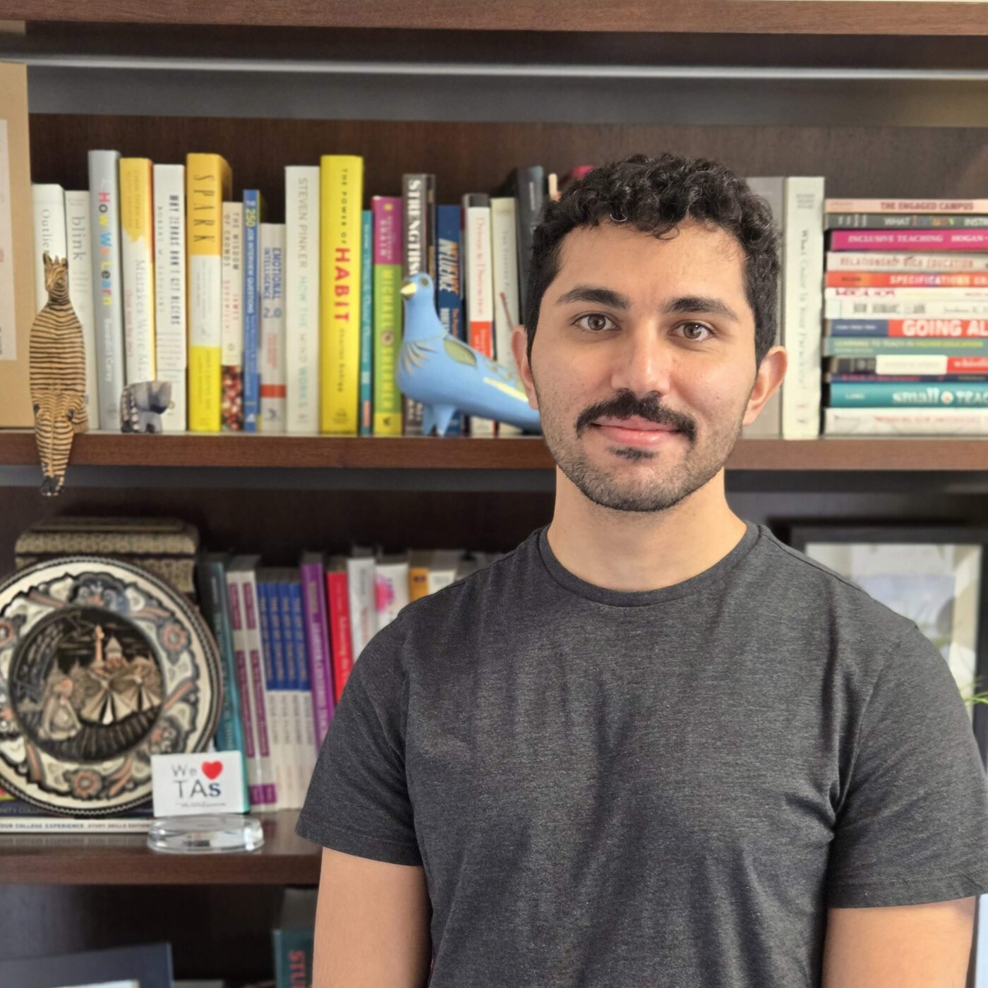 Ehsan Asadollahi smiling in front of a bookshelf